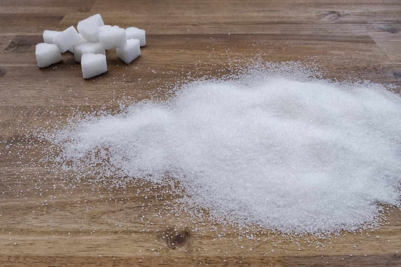 Sugar cubes on a table with some sugar sprinkled on the table