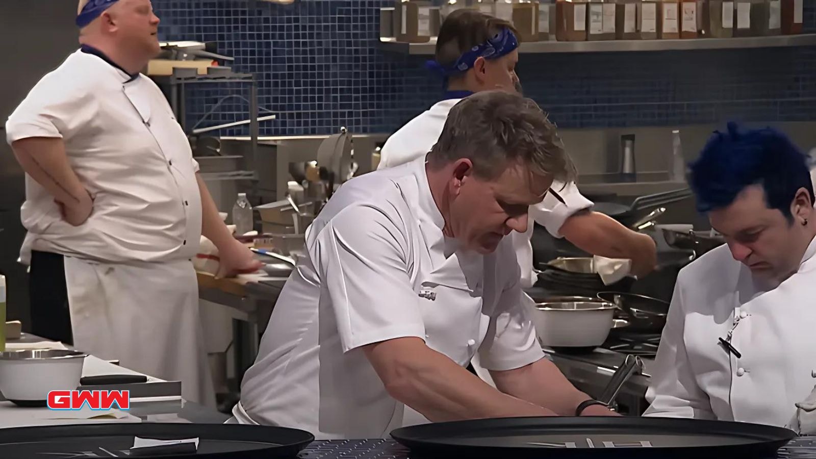 Gordon Ramsay and contestants focused on meal preparation in kitchen