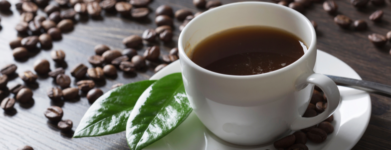 A cup of fresh coffee with coffee beans on the background