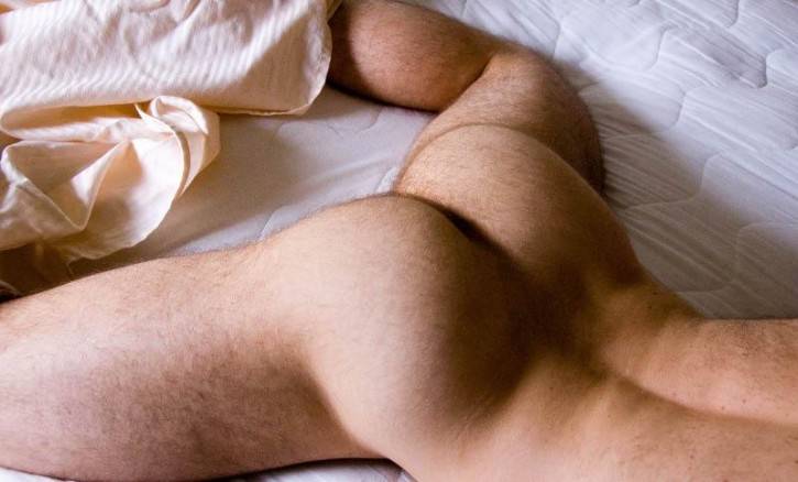 gay naked male in bed showing off his lightly hairy bubble butt