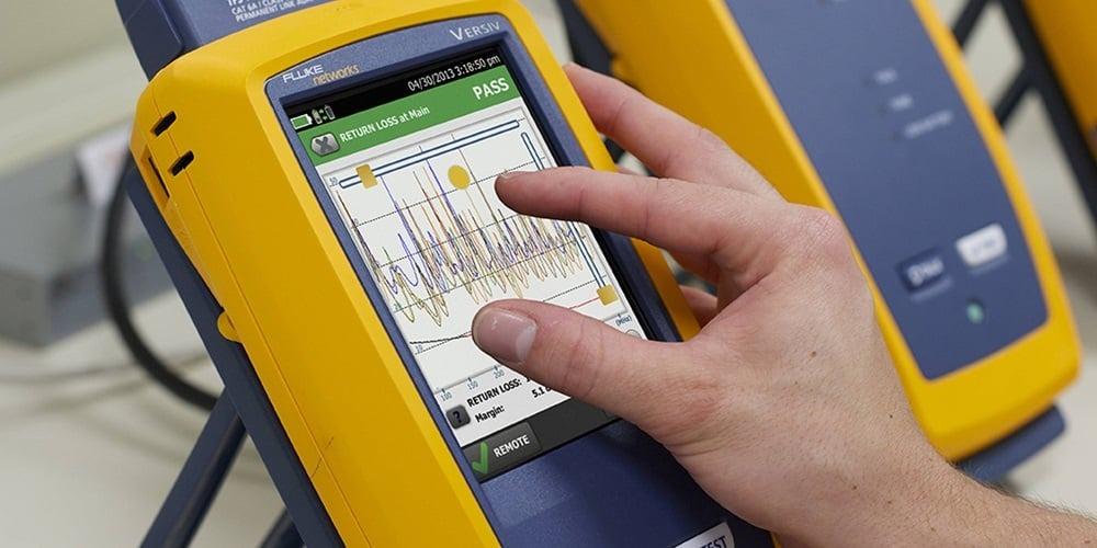 An installer using a Fluke certifier to test a newly installed patch panel link.