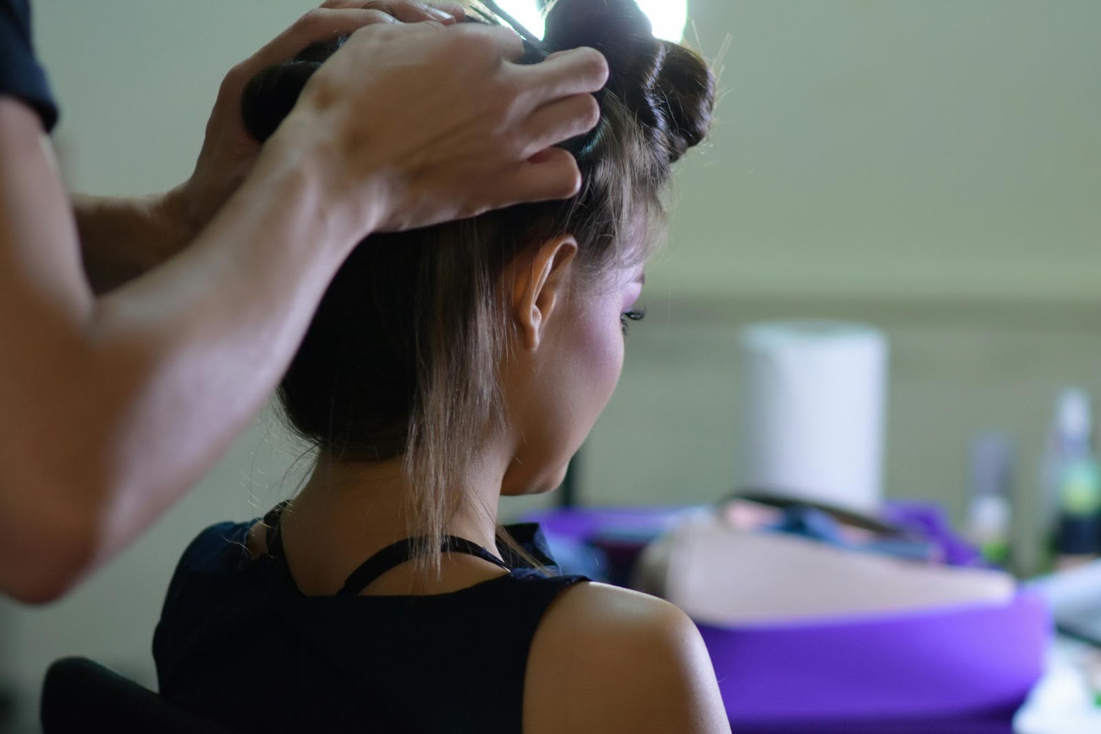 Hairstylist parting client’s hair for clip-in extension placement
