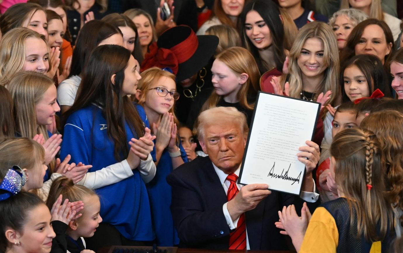 A person holding a piece of paper with a group of people clappingDescription automatically generated