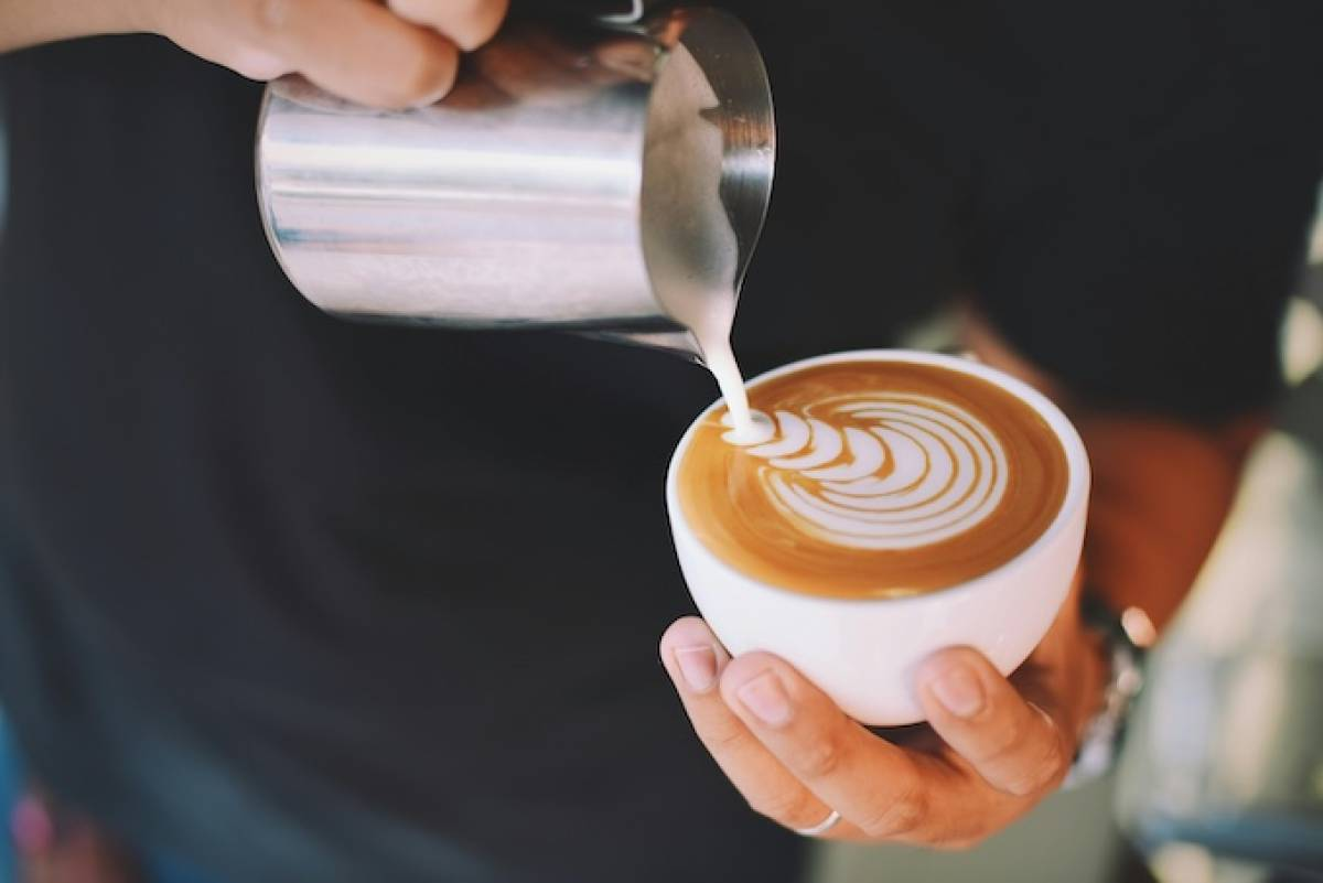 A man pours foamed milk into a latte