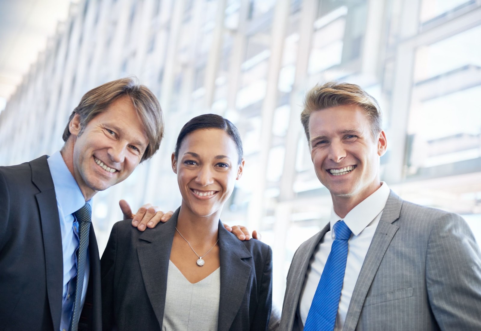 Two men and a woman in suits smiling. 