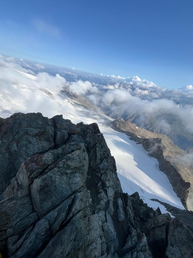A mountain peak with snow and cloudsAI-generated content may be incorrect.