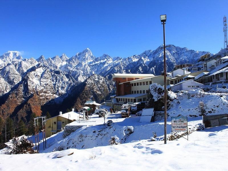 Auli, Uttarakhand, a stunning ski destination, with snow-covered slopes, coniferous forests, and panoramic views of the Himalayas.