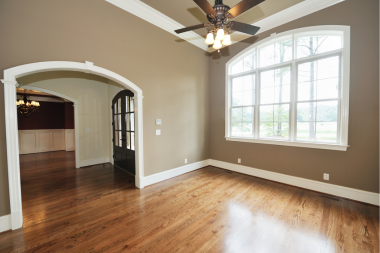 hardwood vs luxury vinyl flooring comparing interior upgrades living room with ceiling fan and large windows custom built michigan