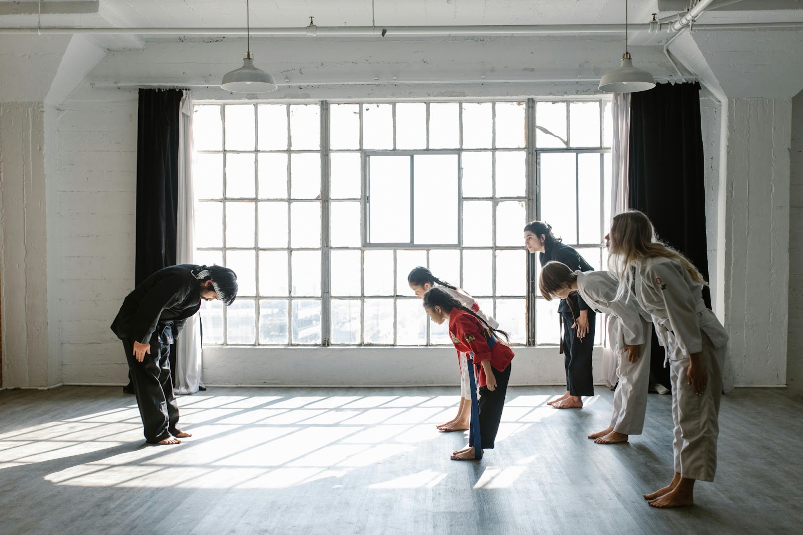 A group of martial arts students bowing in unison in front of their instructor, who is also bowing, in a formal gesture of respect during a training session.