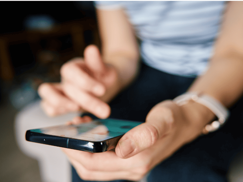 Pessoa usando um smartphone, com foco nas mãos e na tela do aparelho.