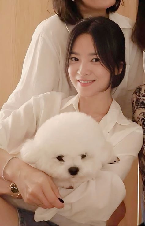 This contains an image of Jeon Yeo Been holding a small white dog in her arms