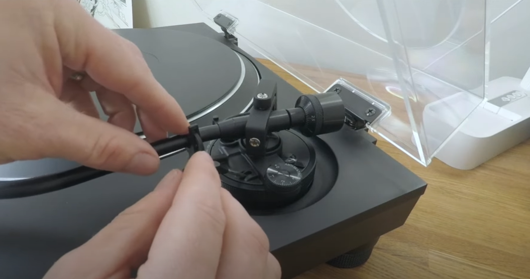 A person adjusting the tonearm on a turntable.