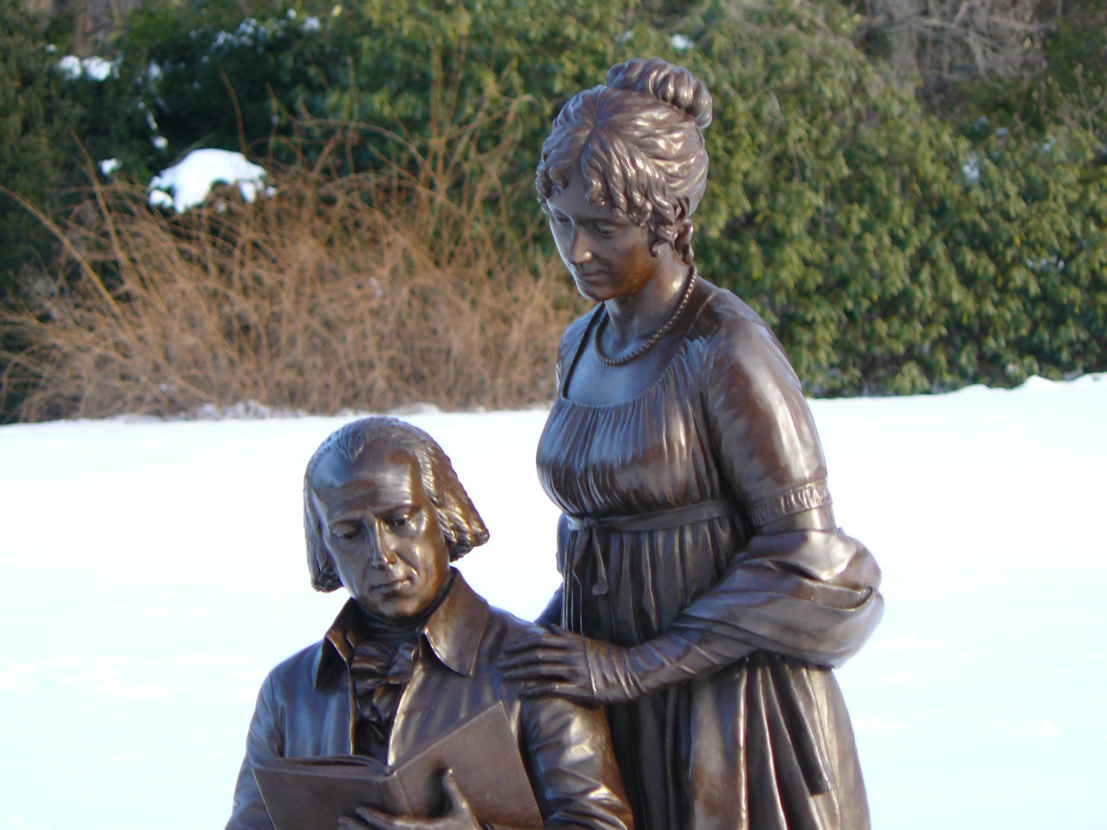 Bronze statue of James and Dolly Madison. James is seated reading and Dolly, standing, looks down over his shoulder,