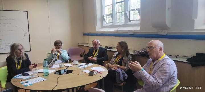 A group of people sitting around a round tableDescription automatically generated