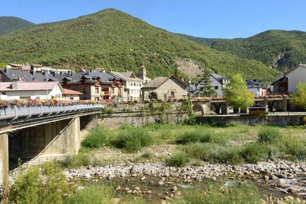 Vista del pueblo de Biescas con puente sobre el río Gállego y montañas al fondo

