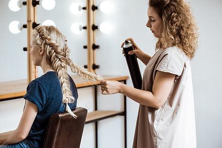 A professional is hair styling a client hair's 