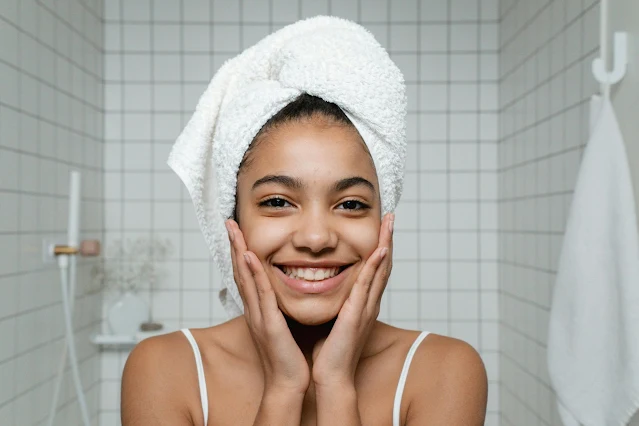 woman smiling with clear skin in bathroom with towel on head