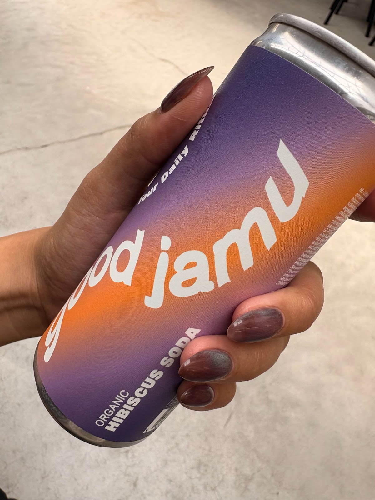 Good Jamu's purple hibiscus soda can being held by a person