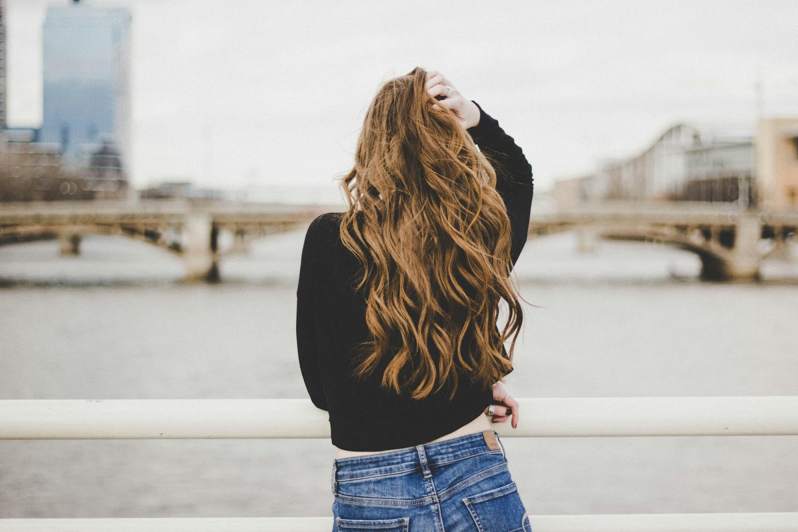 A woman with long, voluminous hair standing near a railing, showcasing the natural blend of micro link hair extensions.