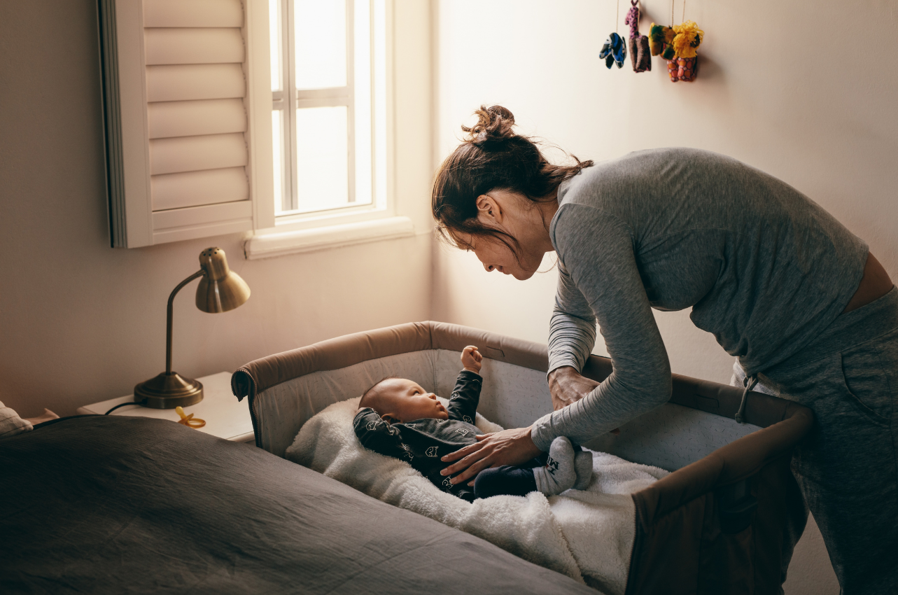 Mom putting her baby to sleep in crib // Healthier Baby Today