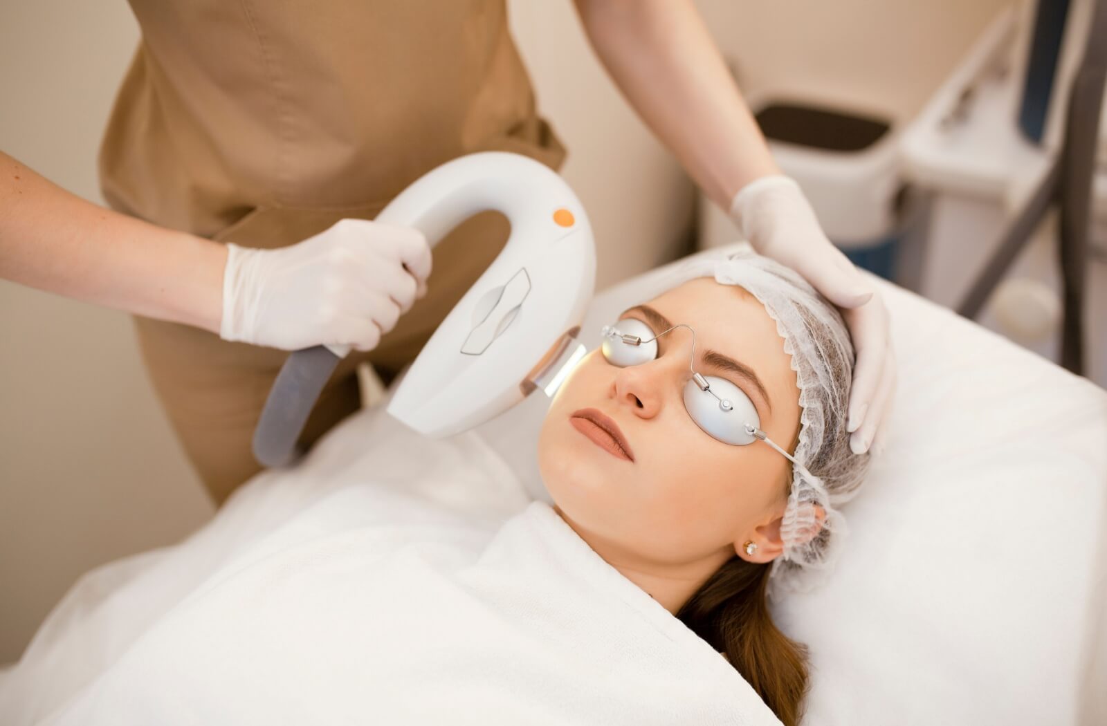 A patient wearing eye shields undergoes IPL treatment from their doctor.