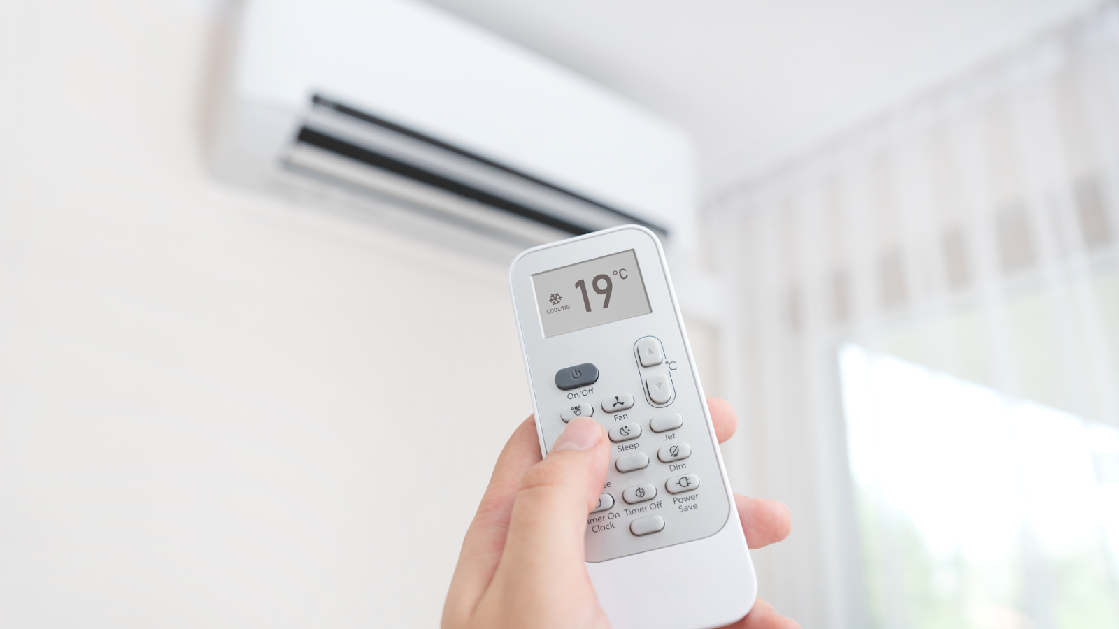 Seseorang sedang memegang remote AC/Sumber: Canva