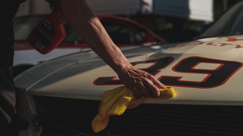 A man is cleaning the car with a microfiber cloth.