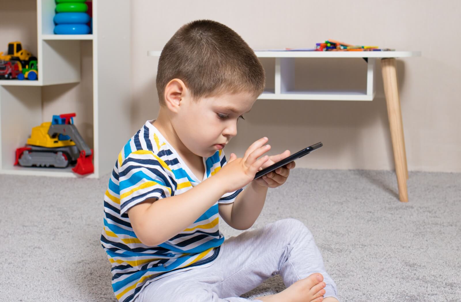 A young child with myopia holds a phone too close to their face because they can't see it clearly at a distance.