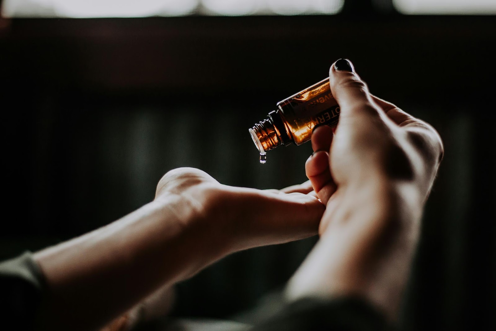 A close-up of hands pouring hair oil, illustrating proper care and maintenance techniques for micro link extensions.