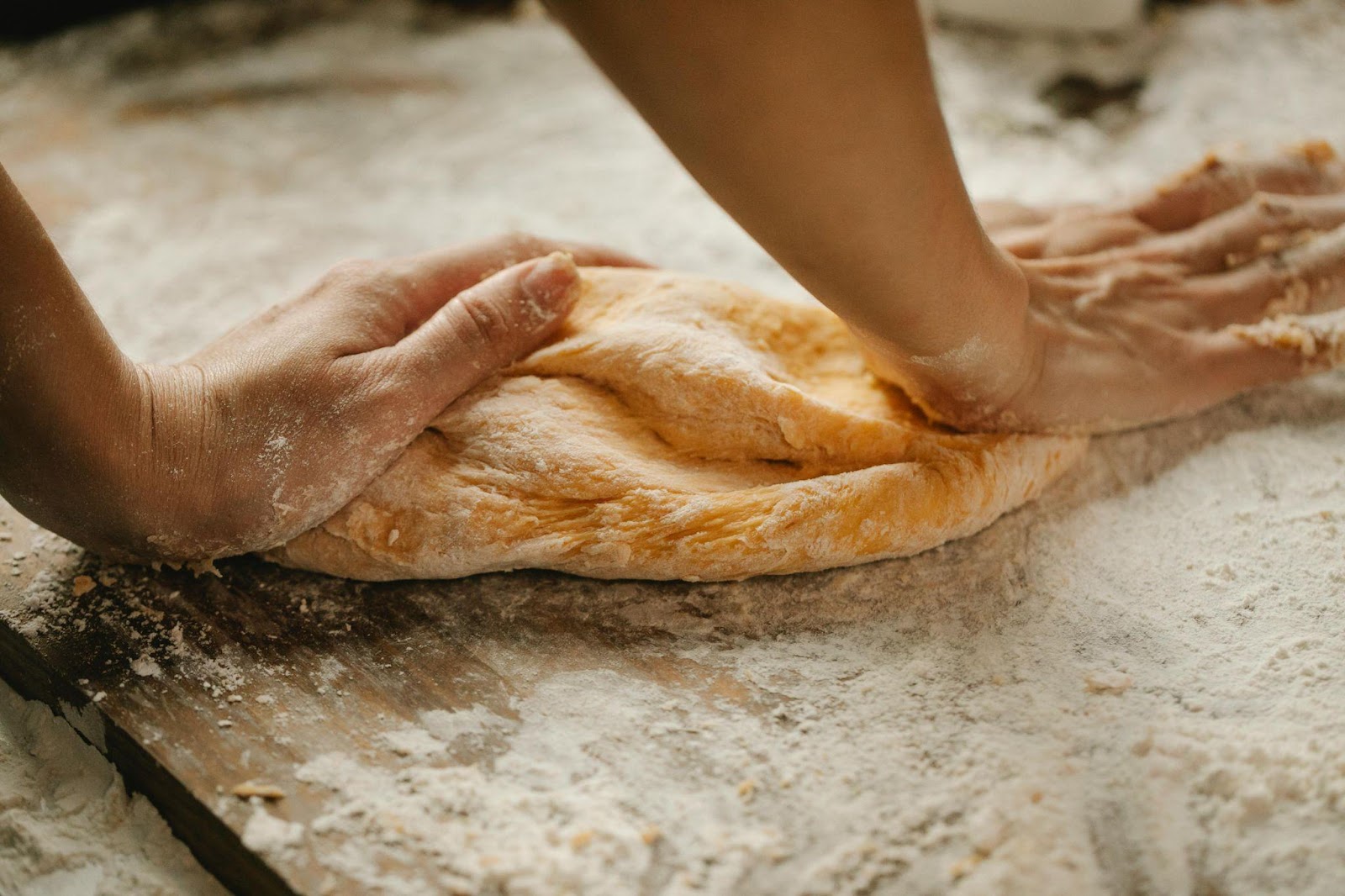 A person kneading dough using flour 