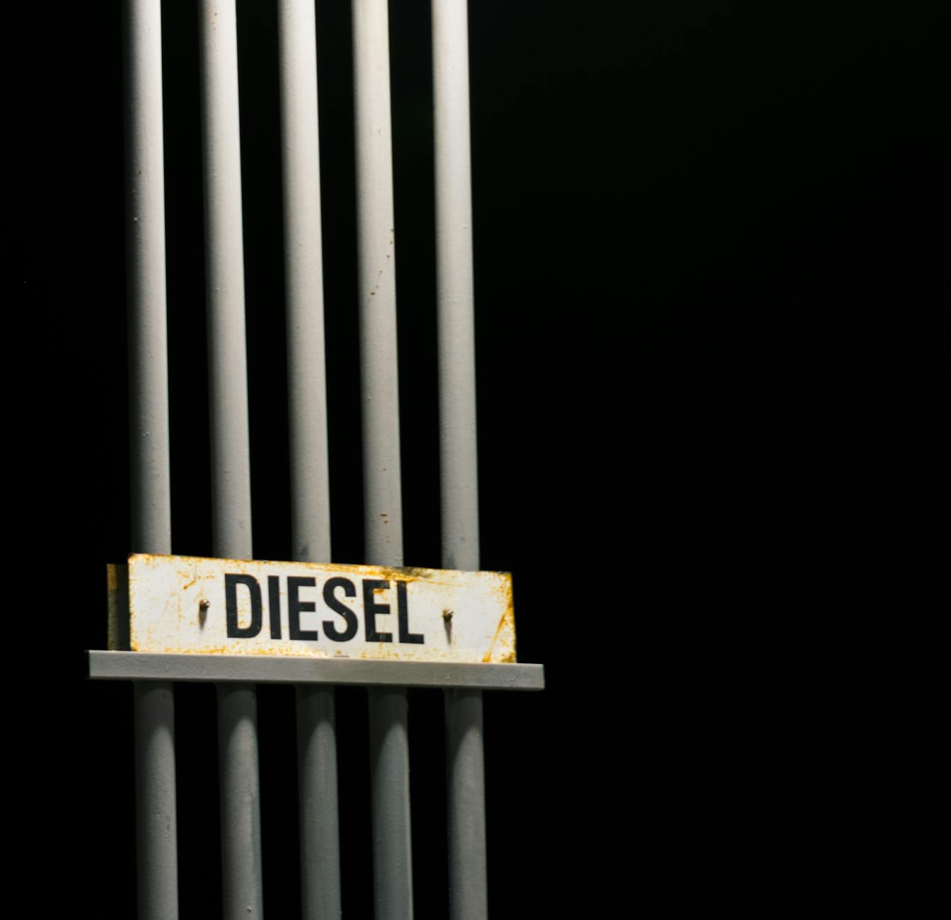 Diesel fuel sign on metal pipes against a dark black background at night.