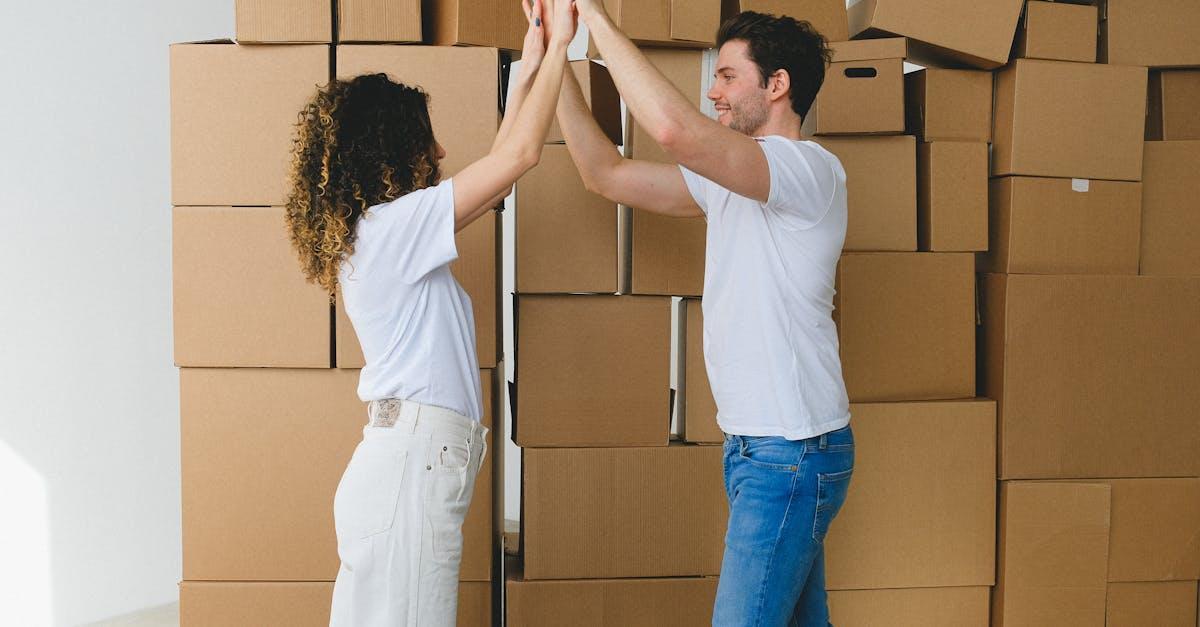 Joyful couple high-fiving in their new home surrounded by moving boxes.