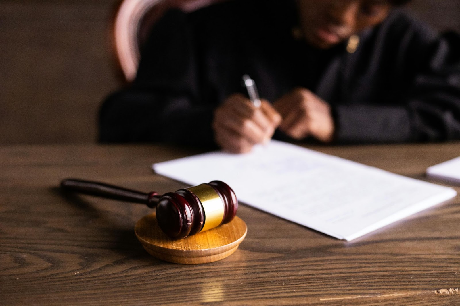 A judge with a gavel is writing notes in court. 