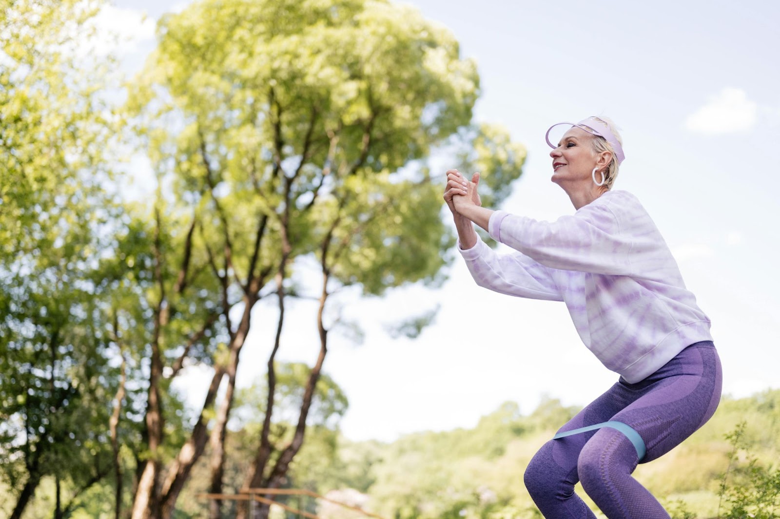 A senior squatting and using a resistance band to do so