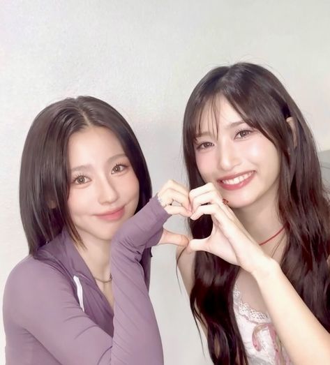 This contain (G)I-DLE's Miyeon, and IVE's Liz   posing for the camera with their hands in the shape of a heart