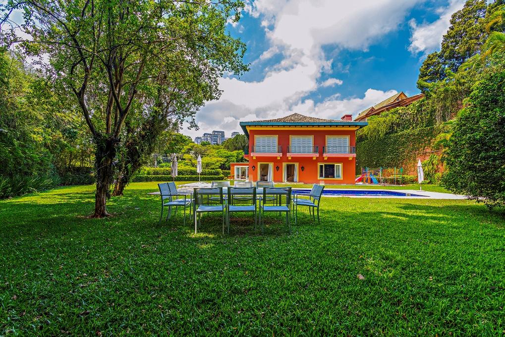 Casa exclusiva com ampla área social e vista para o verde e piscina rodeada por palmeiras