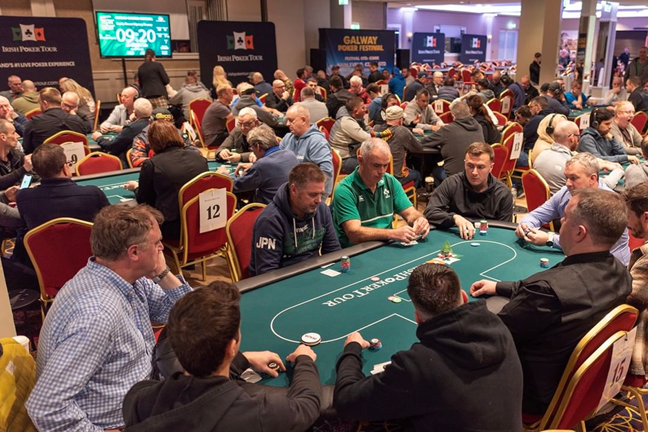 Large Irish Poker tournament with players seated at multiple tables in an indoor venue.
