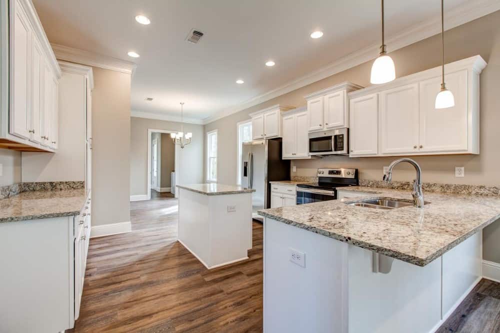Kitchen with stainless steel appliances, white cabinetry, and a peninsula topped with small glass pendants.
