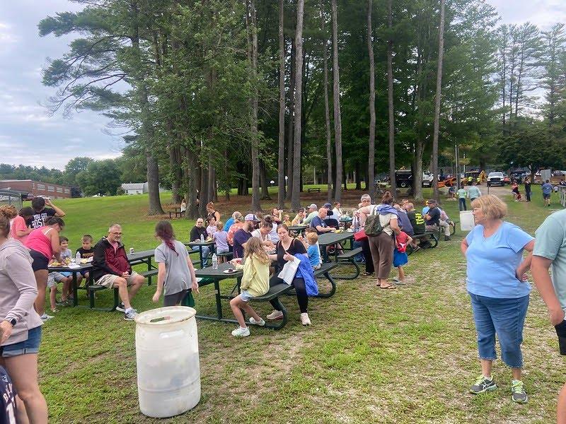 A group of people sitting at picnic tables

Description automatically generated