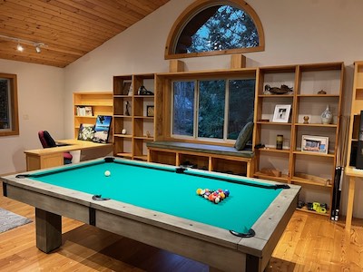 Poole table in a main level room with light coloured wood surroundings and large windows in the background.