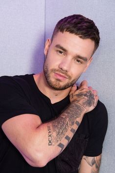 A picture of  Liam Payne on black cloth with hand on his shoulders 