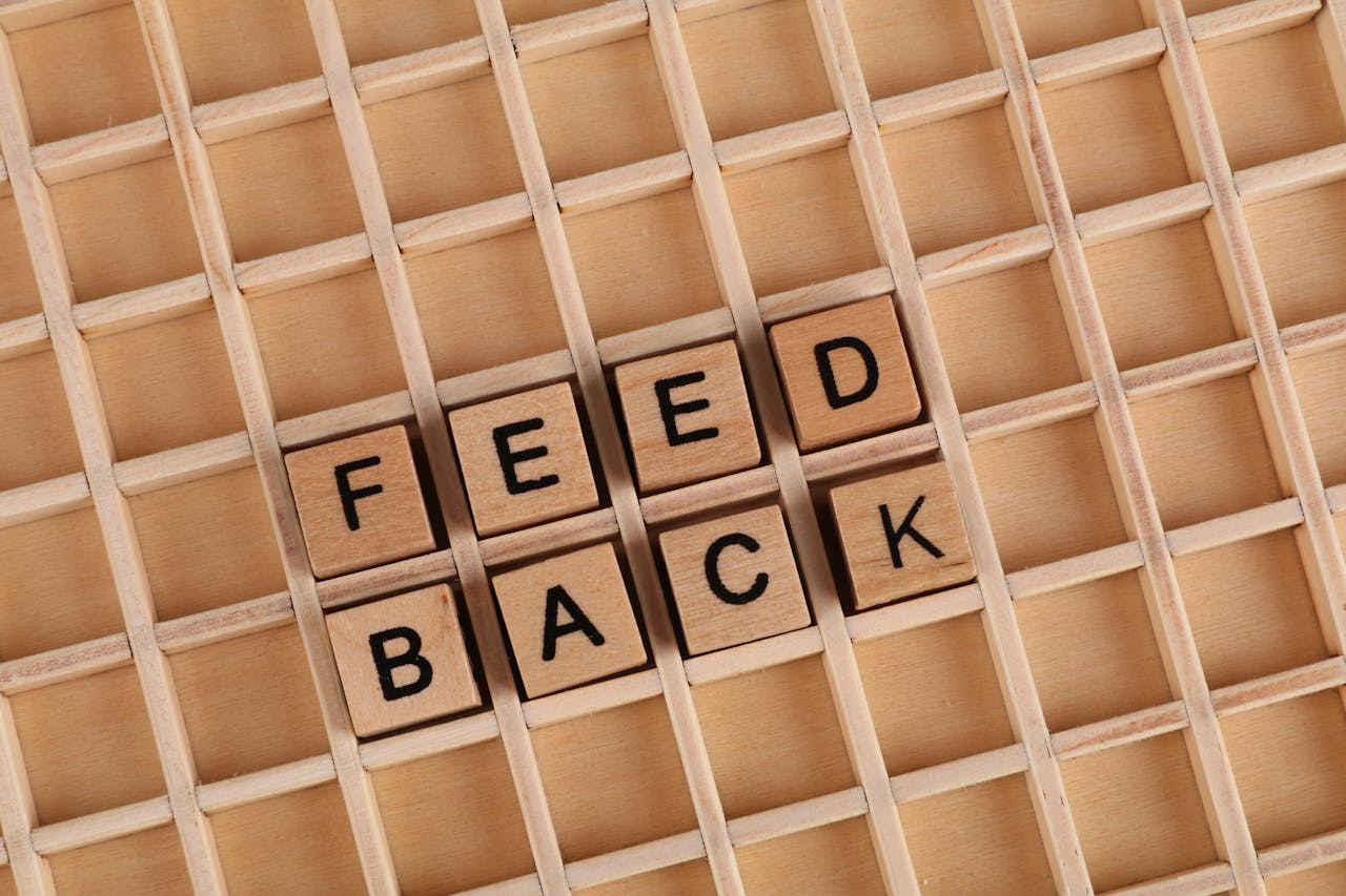 The word 'FEEDBACK' spelled out in wooden block letters inside a compartmentalized box, symbolizing the organization and importance of feedback in various contexts.