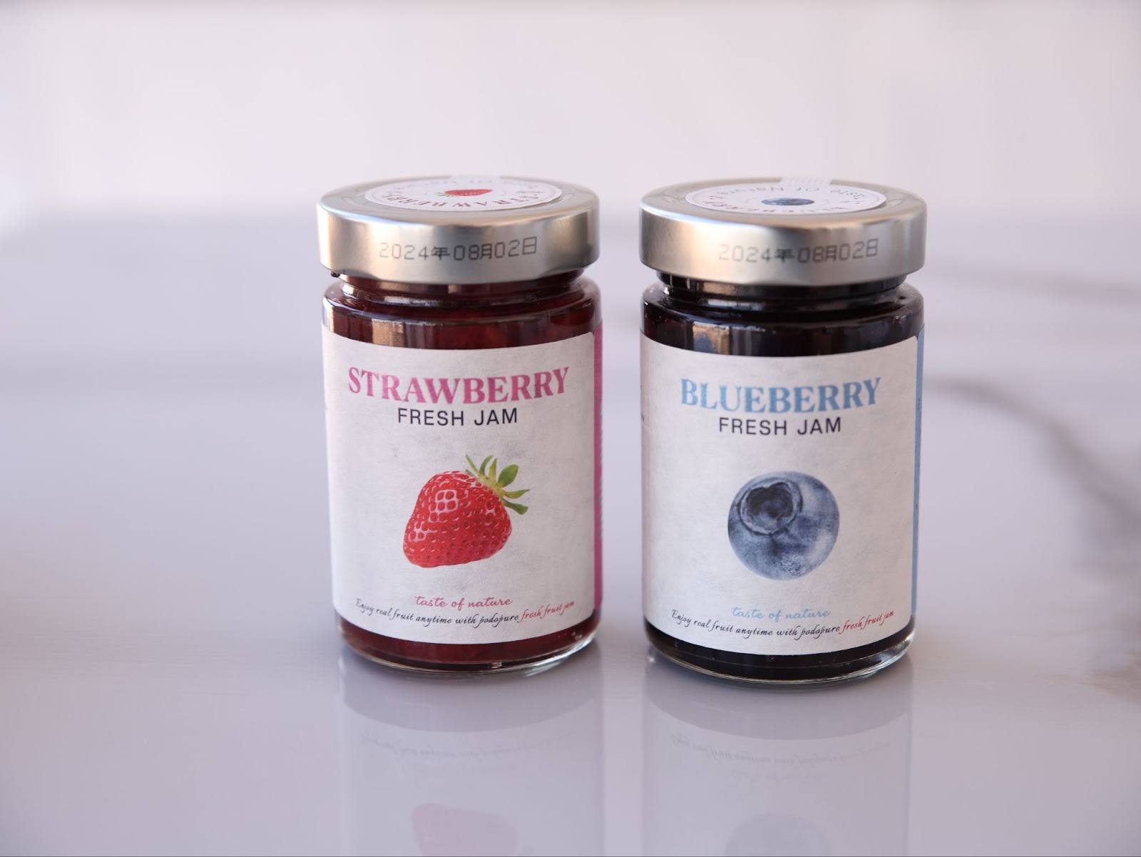 A jar of strawberry jam and a jar of blueberry jam. 