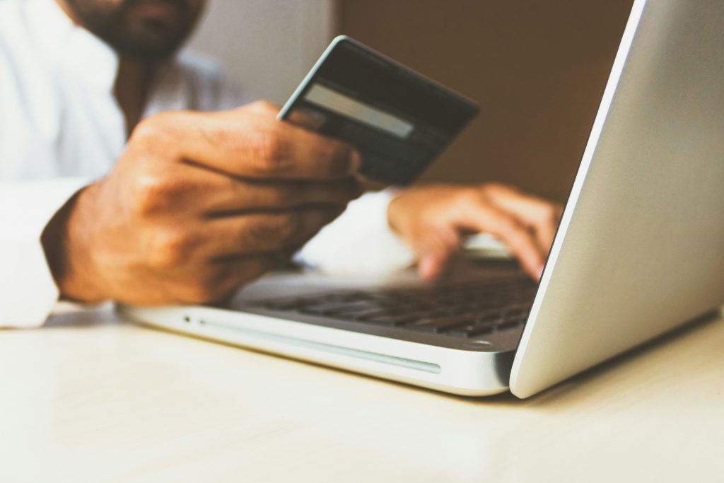 A close-up of a person holding a credit card in one hand while using a laptop with the other, symbolizing online purchases or transactions. This image represents e-commerce businesses and online service providers leveraging 'Meta ads' and 'meta ads manager' to drive sales and increase conversions. It reflects the importance of effective 'facebook ad targeting 2024' to attract customers and address challenges like 'meta ads not performing' for businesses looking to optimize their advertising strategy.