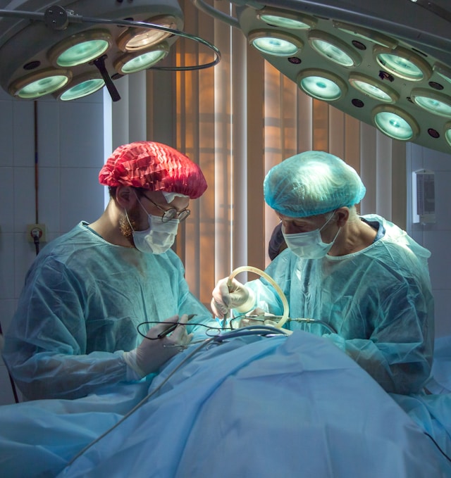 Two surgeons in surgical gowns and masks perform surgery under bright operating room lights equipped with ergonomic design.