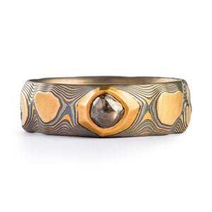 Mokume gane mens ring, made with yellow gold, palladium and oxidized silver. Patterned to resemble a rocky dimensional texture, with a large diamond crystal set into the band.