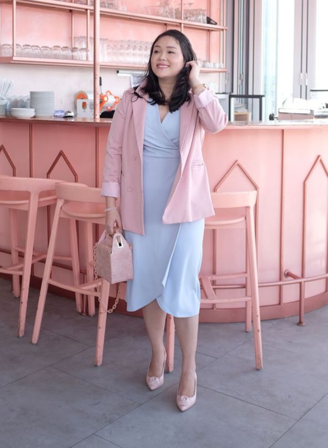 Wanita dengan dress biru muda dan blazer pink.