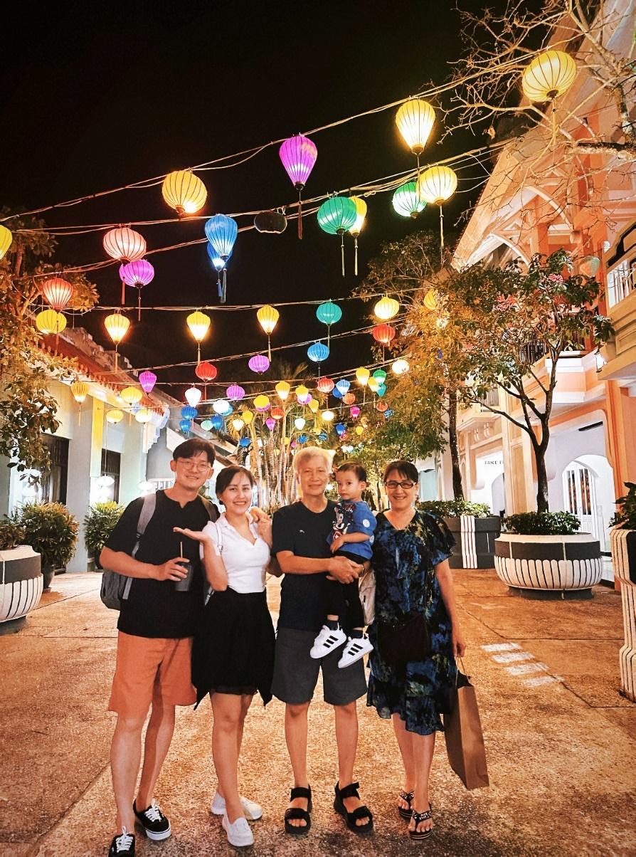 A group of people standing under a string of colorful lights

Description automatically generated