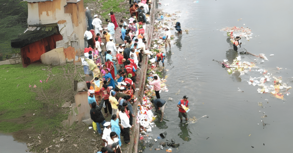 A large group of individuals is positioned by a river, highlighting water pollution issues Ghat..

