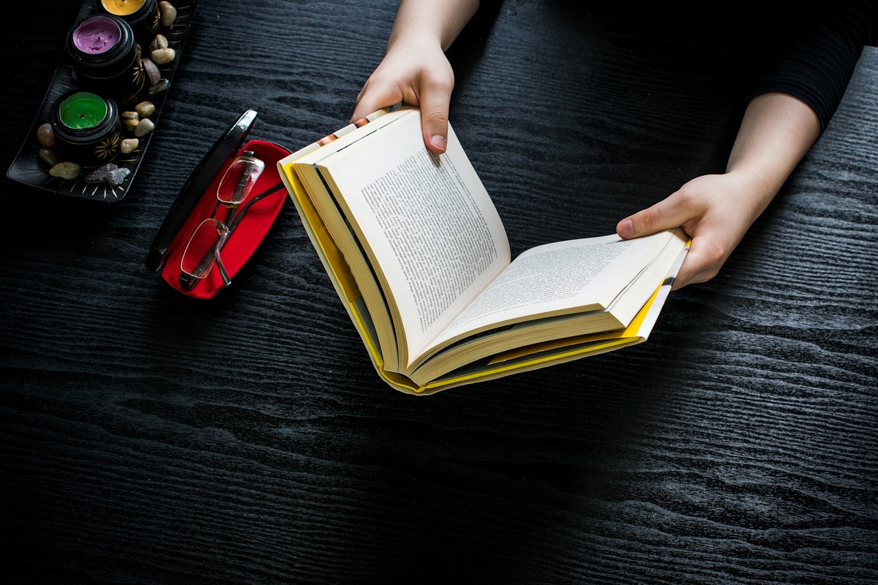 A person reading a book. Dark wood background. 